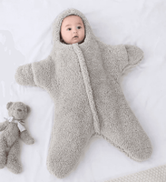 Baby in soft gray fleece onesie with hood, lying on white surface