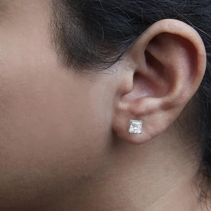 14K white gold princess cut diamond stud earrings worn on an ear, demonstrating their versatile and understated elegance.