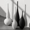 Set of black and white Jingdezhen modern minimalist handmade art vases with sleek, elongated designs displayed on a concrete floor.