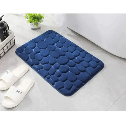 Navy blue super absorbent shower room floor mat with a pebble-like texture, placed near a bathroom setup.