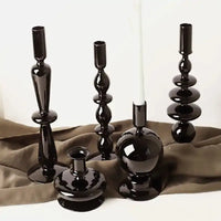 Set of black Rue glass candlesticks in various elegant shapes, adding timeless elegance to home decor on a neutral fabric backdrop.