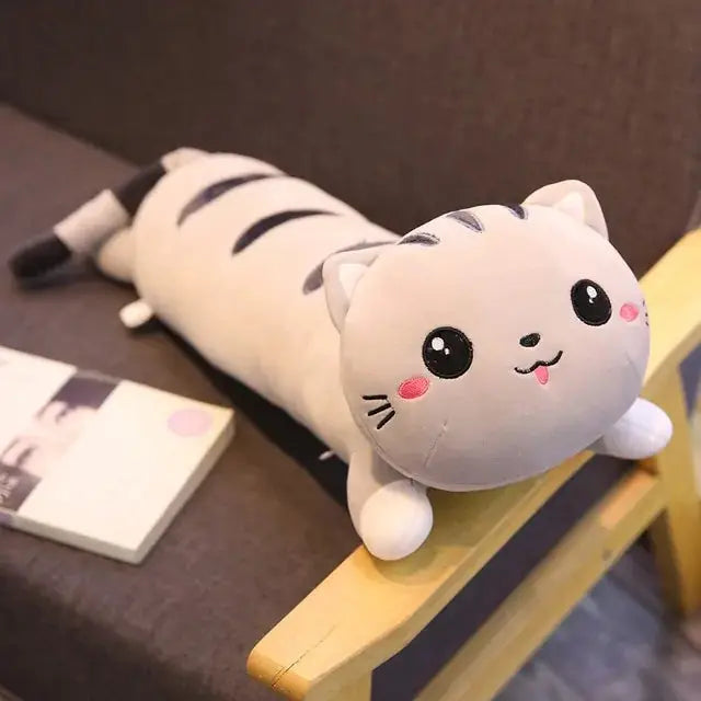 Cute Cat Pillow Plush Toy featuring a gray and white cat design with pink cheeks, lying on a sofa. Perfect for cuddling and decor.
