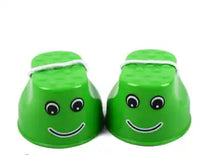 Green children's outdoor stilts with cheerful face design and rope handles, ideal for enhancing motor skills through outdoor play.
