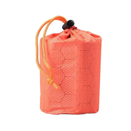 Orange drawstring pouch with hexagonal pattern, designed for storing the emergency sleeping bag for easy portability.