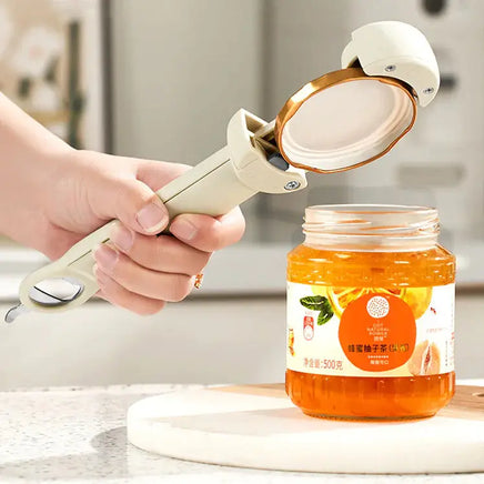 White stainless steel labor-saving cap screw gadget opening a jar of orange marmalade, showcasing its efficiency and ease of use.