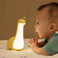 Yellow dinosaur night light glowing warmly as a baby gazes at it, creating a magical and engaging bedtime experience.