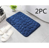 Navy blue super absorbent shower room floor mat with a pebble-like texture, sold as a 2-piece set, placed near a bathroom setup.