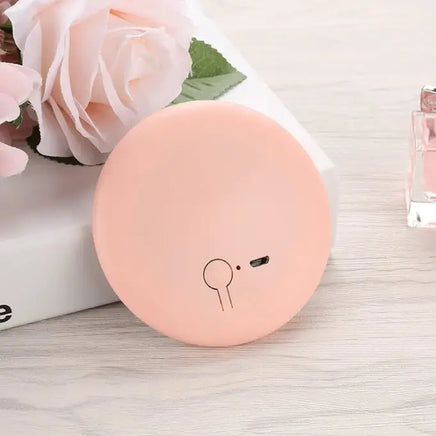 Pastel pink Pocket LED Makeup Mirror placed on a table with decorative flowers, highlighting its elegant and portable design.