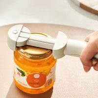 Close-up of a white stainless steel labor-saving cap screw gadget securely gripping a jar lid, demonstrating its functionality.