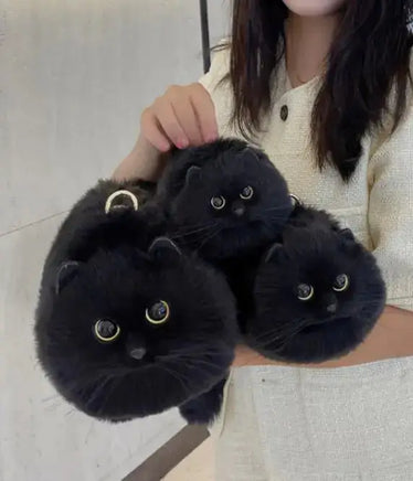 Three black handmade plush cat bags held together, featuring golden eyes and soft plush material, ideal for cat-themed accessories.