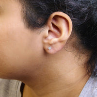 14K white gold princess cut diamond stud earrings worn on an ear, offering a subtle yet luxurious touch to any outfit.