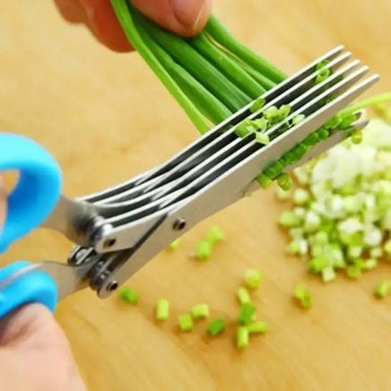 Blue-handled multifunctional green onion scissors cutting green onions into small pieces on a wooden surface, perfect for kitchen use.