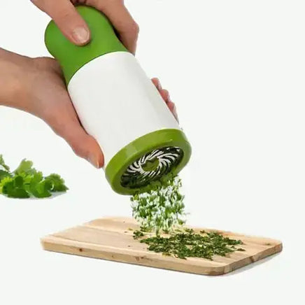 Herb grinder from the Essential Kitchen Five Gadget Bundle in use, finely chopping fresh herbs on a wooden cutting board.