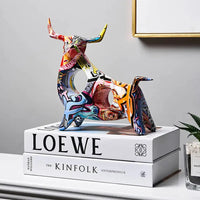 Colorful Modern Art Graffiti Cow Figurine with intricate graffiti patterns, placed on stacked books for stylish decor.