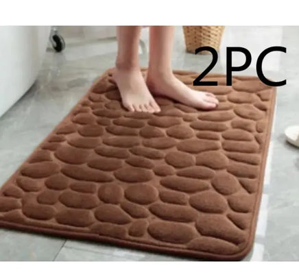 Brown super absorbent shower room floor mat with a pebble-like texture, sold as a 2-piece set, shown with a person standing on it.