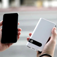 Compact car jump starter held in hand, compared in size to a smartphone, emphasizing its portable and lightweight design.