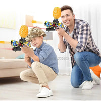 Father and son playing with colorful toy gun blasters equipped with water bead hoppers indoors.