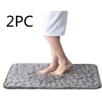 Gray super absorbent shower room floor mat with a pebble-like texture, sold as a 2-piece set, shown with a person stepping on it.