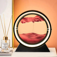 Moving Sand Art Picture Frame featuring pink sand creating flowing designs in a circular frame with a white base, set against a green background.