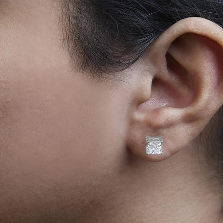 Close-up of 14K white gold princess cut lab-grown diamond stud earrings worn on an ear, emphasizing their sparkle and clarity.