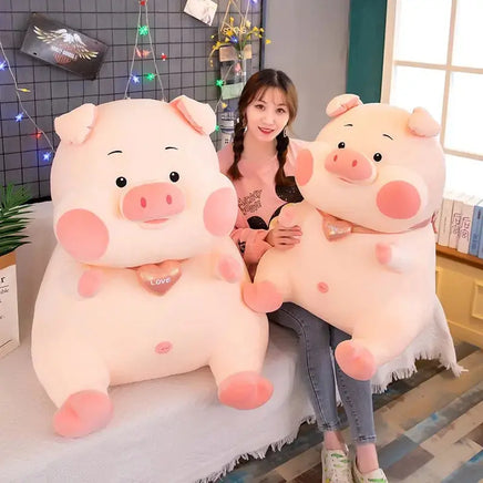 Two large plush pig toys with heart pendants, displayed with a smiling woman in a cozy, decorated room.